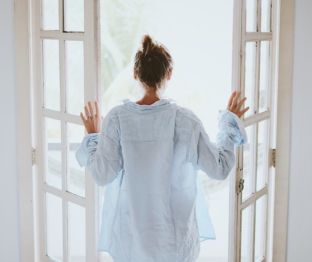 A woman opening french doors to the morning light